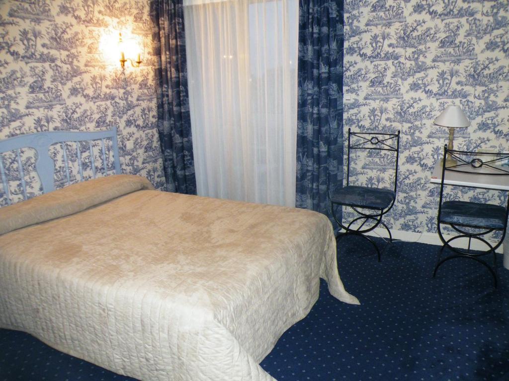 a hotel room with a bed and a chair at Hôtel de L&#39;Avenue in Saintes