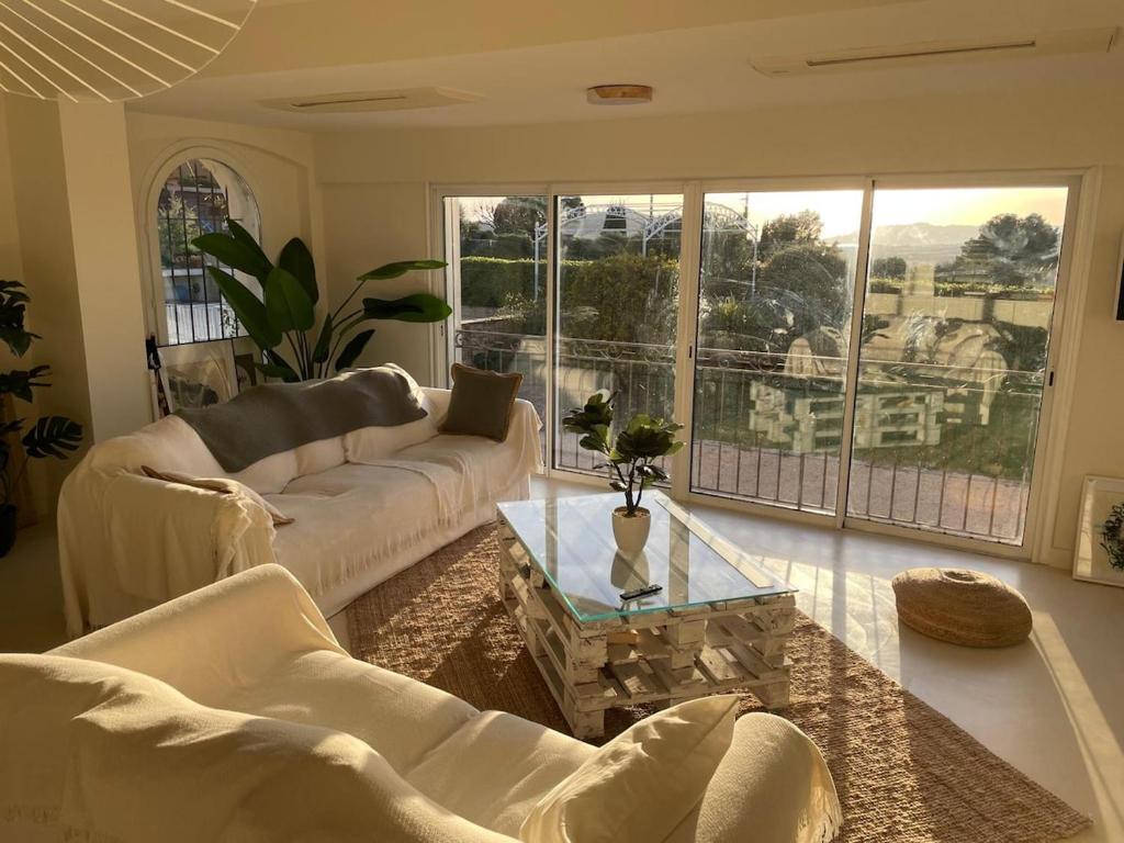un salon avec des meubles blancs et une grande fenêtre dans l'établissement Grande Villa avec Piscine, Pétanque et Vue Mer pour 12 Personnes, au Beausset