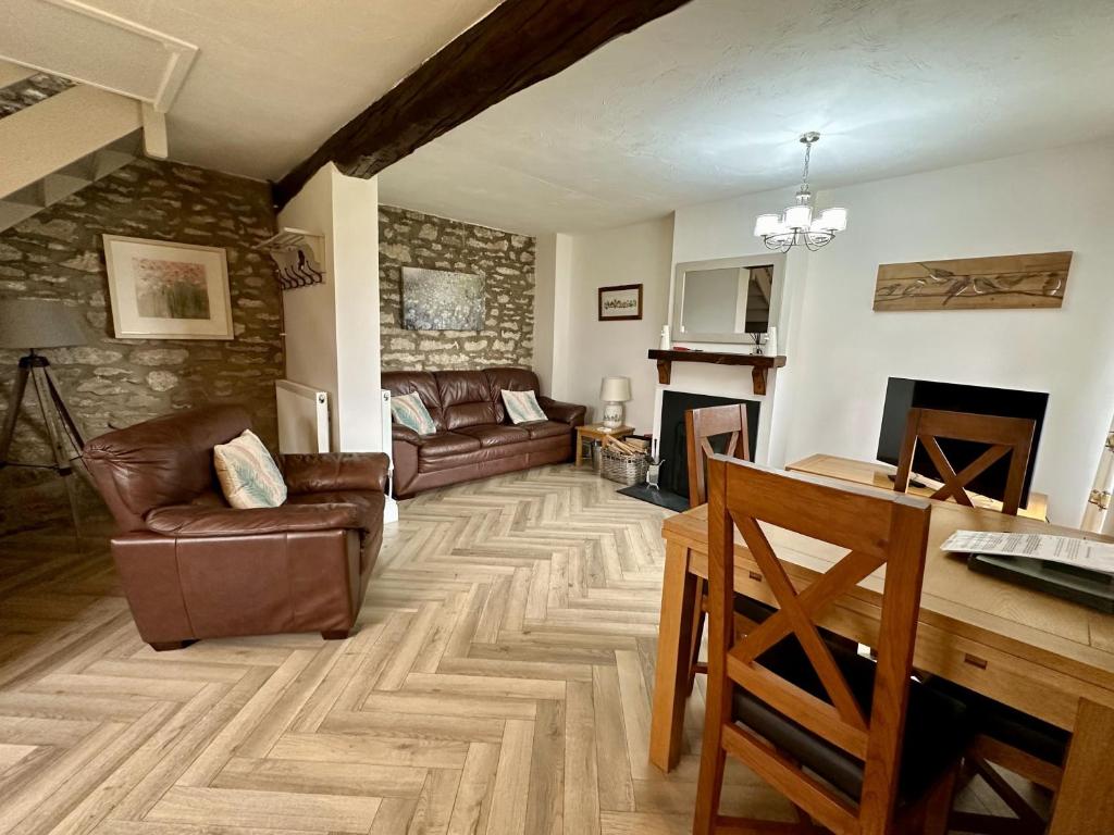 a living room with leather furniture and a stone wall at Bilsdale Cottage in Helmsley
