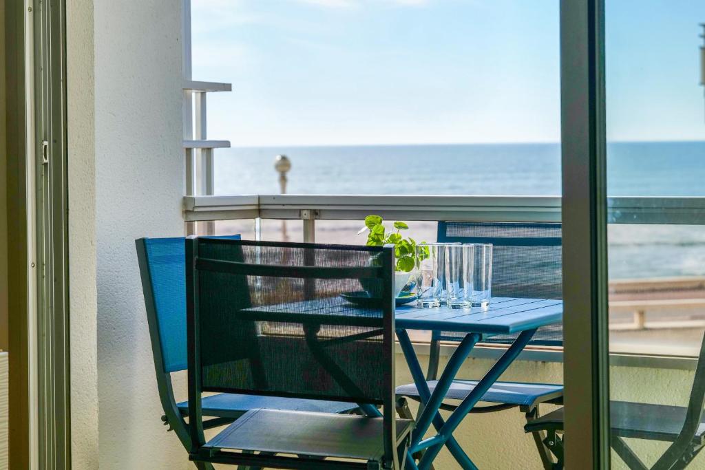 d'une table bleue et d'une chaise avec vue sur la plage. dans l'établissement Bel appartement vue mer - quartier des Présidents - 5 personnes, à Les Sables-dʼOlonne