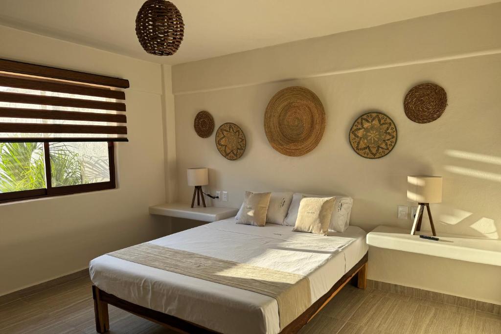 a bedroom with a bed with two lamps and a window at Ixic posada boutique in Zihuatanejo