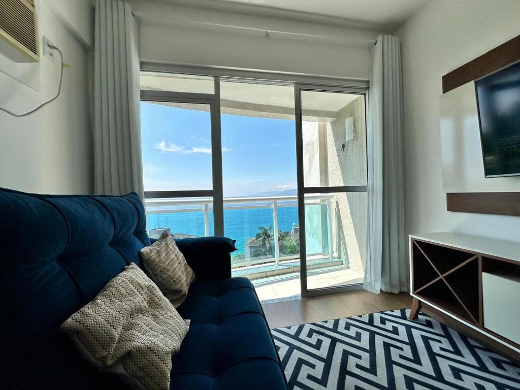 a living room with a blue couch and a large window at Apartamento Bela Vista Porto Real Resort in Mangaratiba