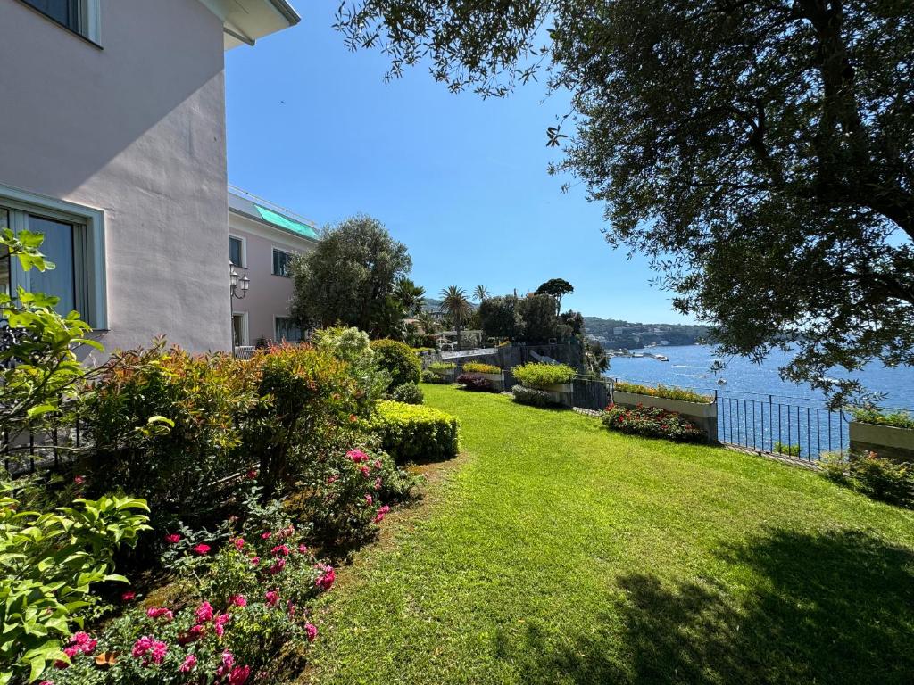 un cortile con fiori e un edificio e l'acqua di Villa Saran a Sorrento