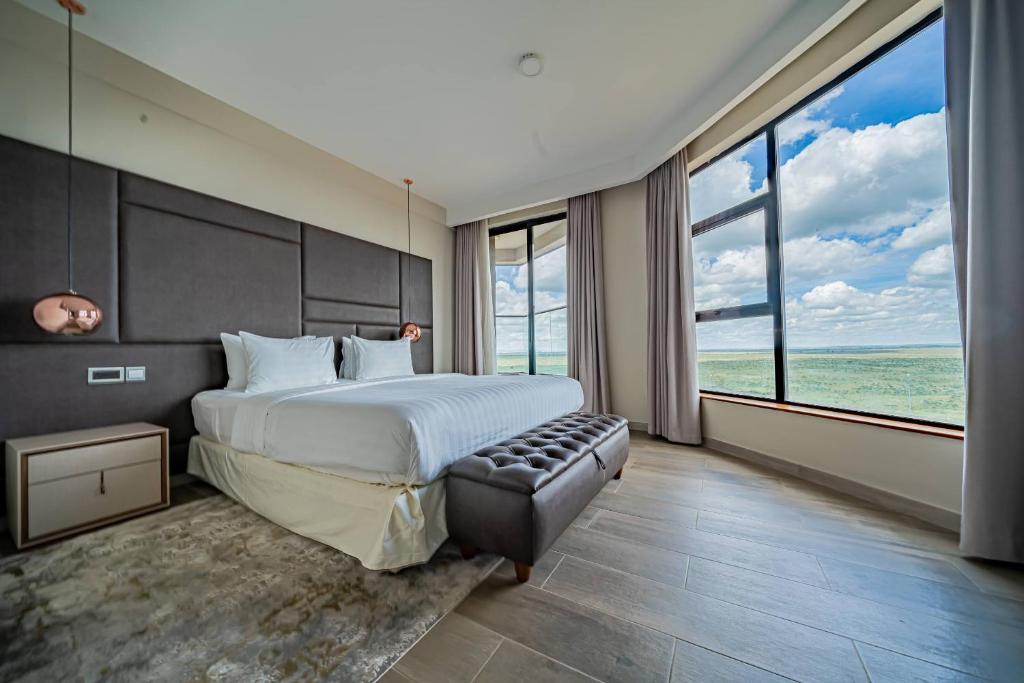 ein Schlafzimmer mit großem Bett und großen Fenstern in der Unterkunft The Curve by the Park Nairobi by TSG in Nairobi
