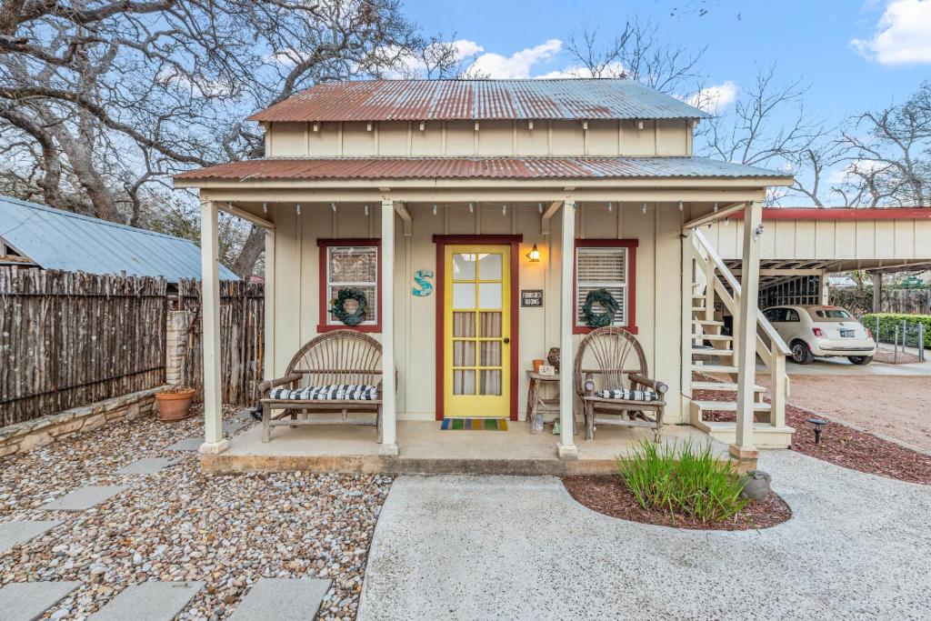 a small house with two benches and a yellow door at Serendipity in Fredericksburg