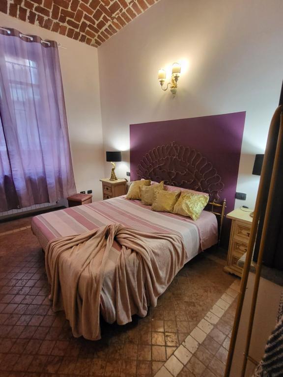 a bedroom with a large bed with a purple headboard at Kiki House in Turin