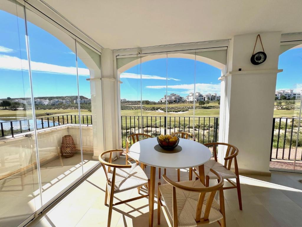 a room with a white table and chairs on a balcony at Stunning frontline apartment with golf views and pool in Sucina