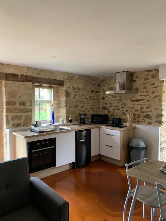 une cuisine avec des armoires blanches et un lave-vaisselle noir dans l'établissement Gîte du merlin, à Plumergat