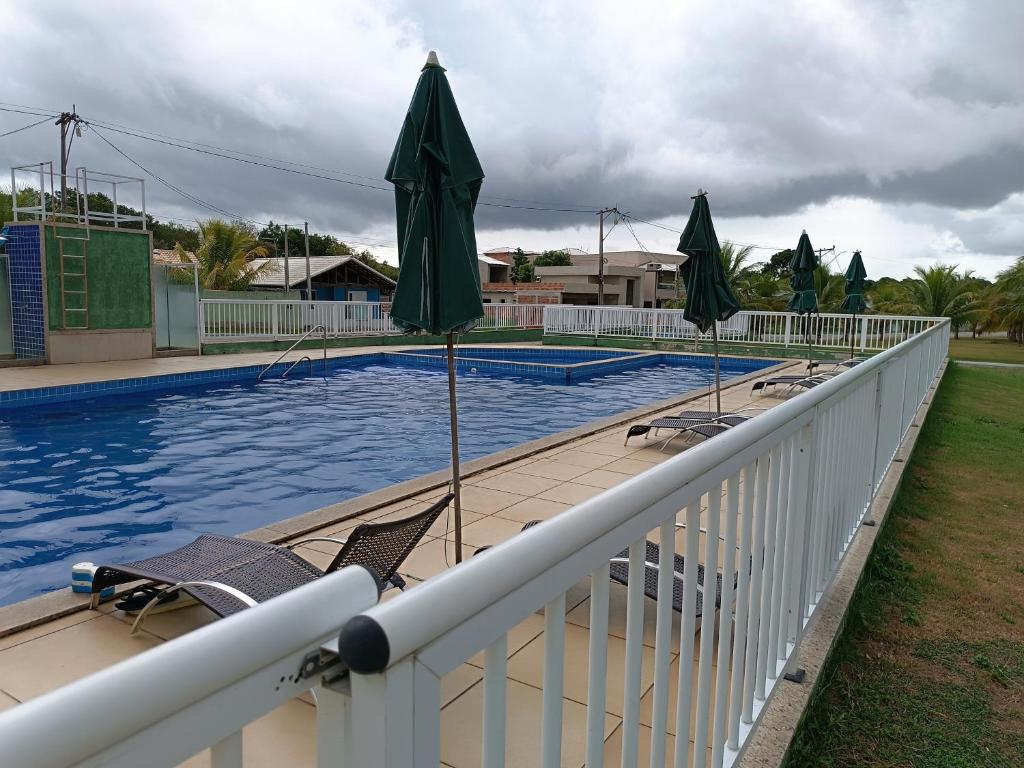 a swimming pool with chairs and umbrellas on a fence at Aconchego in São Pedro da Aldeia