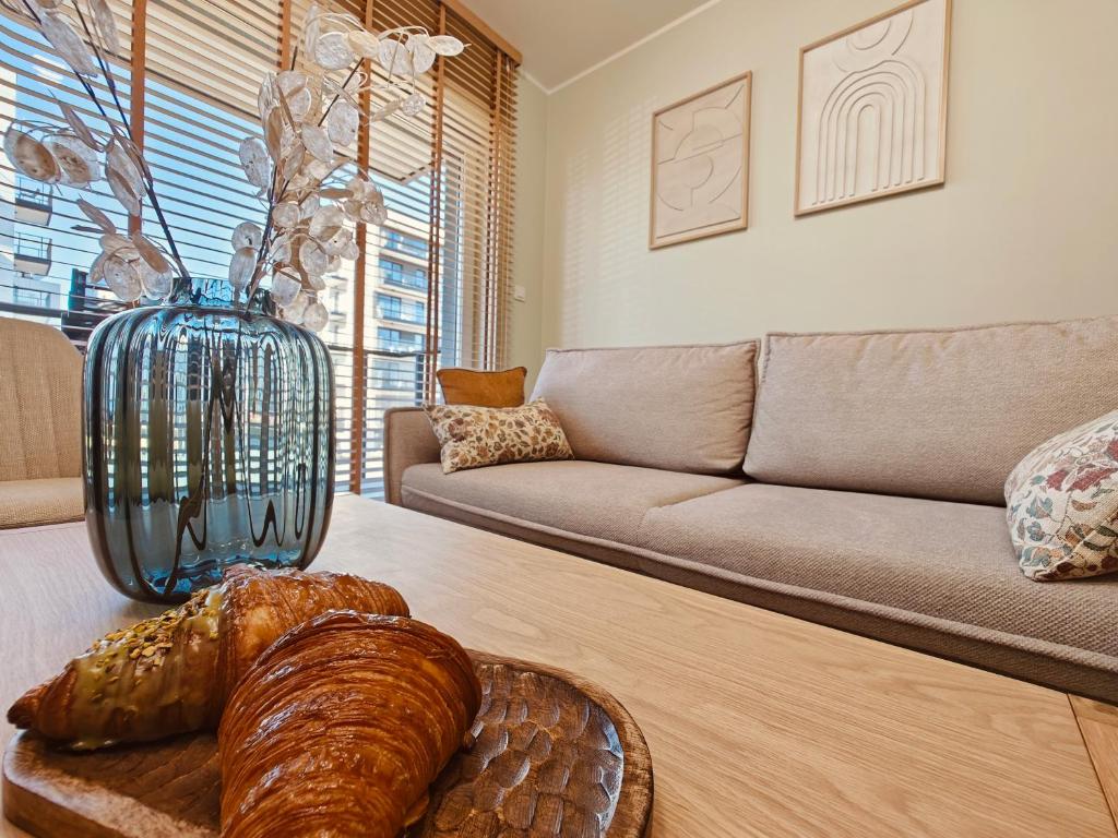 a living room with a couch and a table with a vase at Amber Coast Apartment Gdańsk in Gdańsk