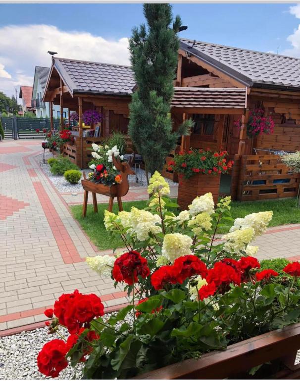 a building with red and white flowers in front of it at Domki letniskowe KEYA in Gąski