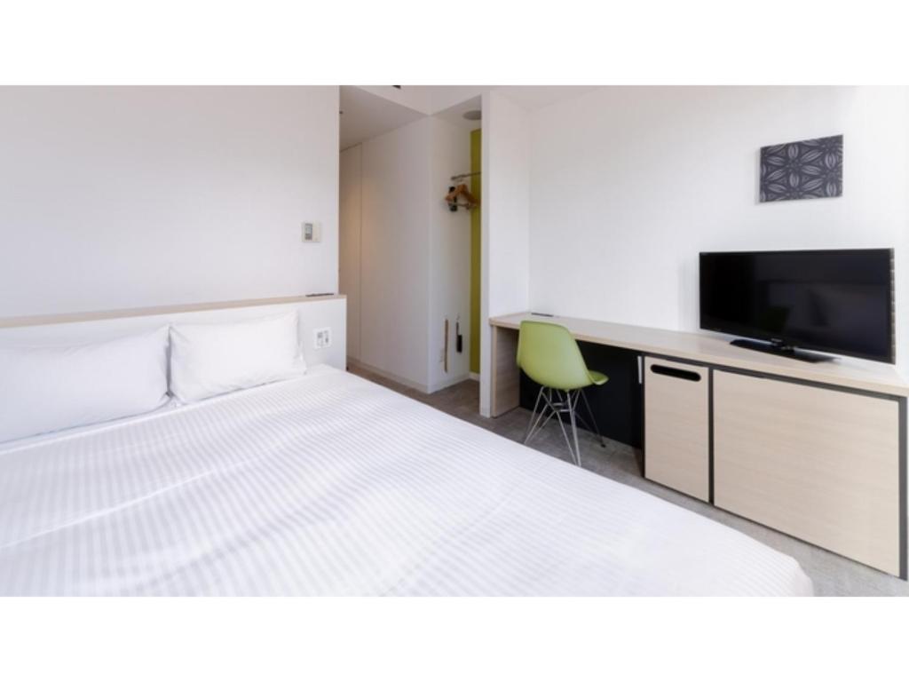 a bedroom with a bed and a desk and a tv at The OneFive Sendai - Vacation STAY 44966v in Sendai