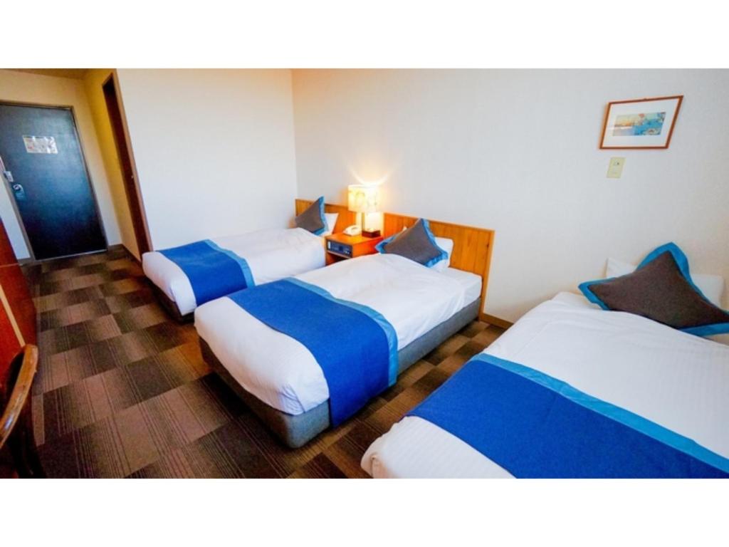 伊勢市にあるHotel Area One Ise Inter - Vacation STAY 38393vのベッド3台とテーブルが備わるホテルルームです。