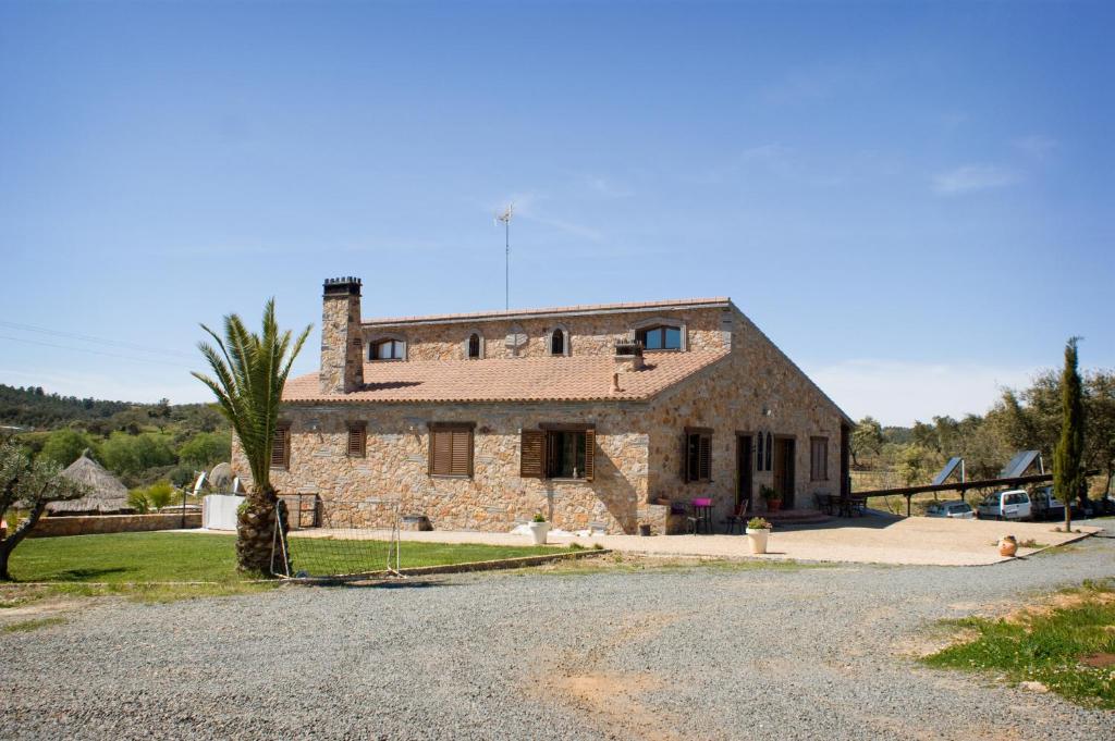 a stone house with a palm tree in front of it at Casa Rural Camino del Alentejo in La Codosera