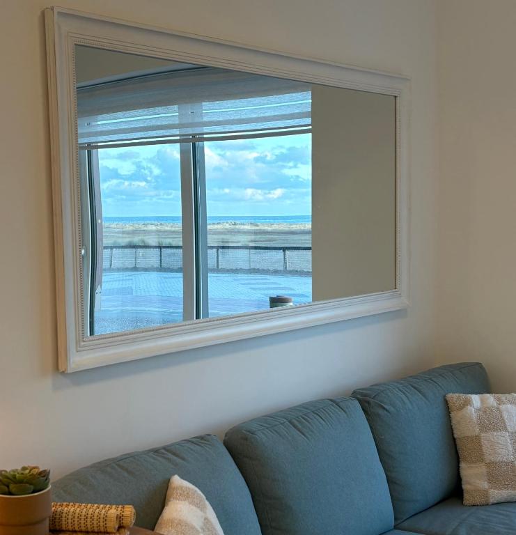 a large window in a living room with a blue couch at SEA VIEW Juweeltje in Knokke-Heist