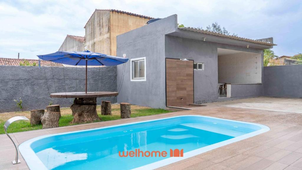 a swimming pool with an umbrella next to a house at Casa ampla com lazer completo na Regiao dos Lagos in São Pedro da Aldeia