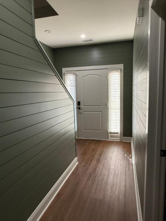 an empty hallway with a white door and wood floors at The Bungalow in Lithia Springs