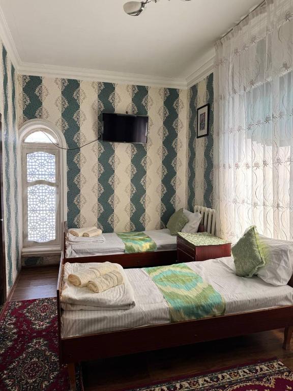 a bedroom with two beds and a window at Abdurauf in Bukhara