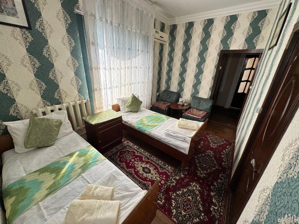 a small room with two beds and a window at Abdurauf in Bukhara