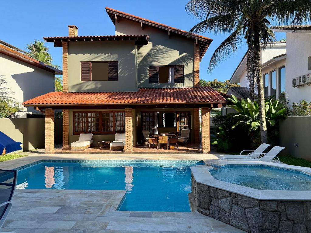 une maison avec une piscine devant une maison dans l'établissement Casa 10 Pessoas Riviera de São Lourenço, à Bertioga