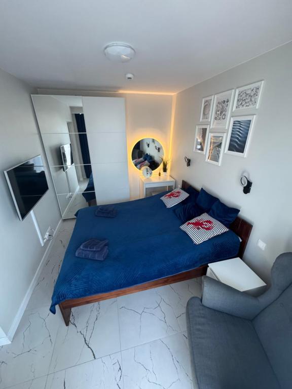 ein Schlafzimmer mit einem blauen Bett und einem Sofa in der Unterkunft Natura Resort Rozewska in Jastrzębia Góra