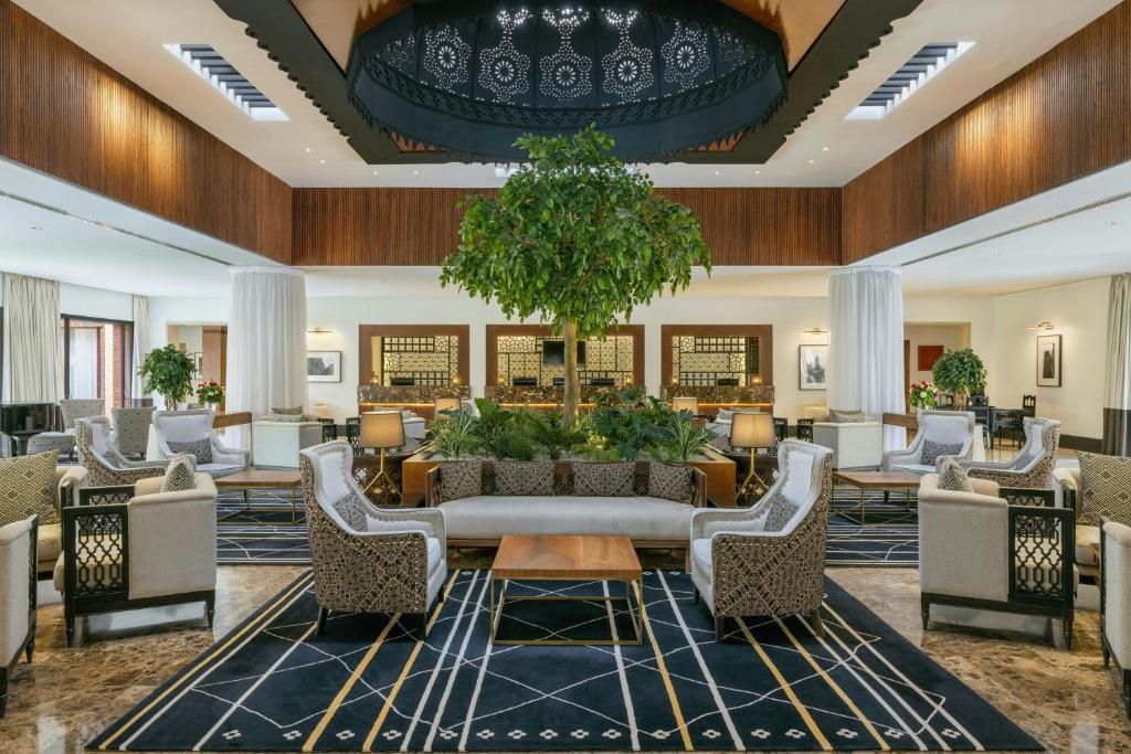 a lobby of a hotel with chairs and a tree at Le Meridien N'fis in Marrakech