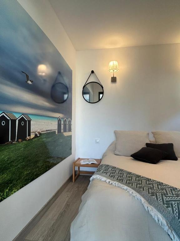 a bedroom with a bed and a painting on the wall at La Cabane in Quiberville