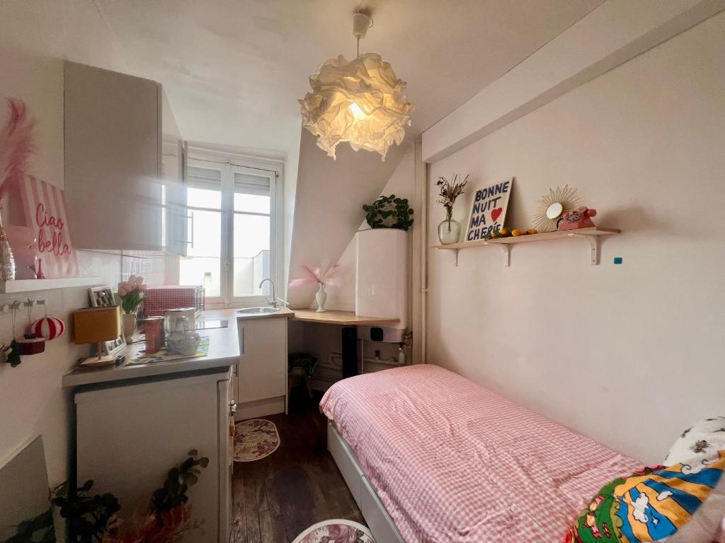 - une petite cuisine avec un lit rose dans une chambre dans l'établissement Paris centre Orsay studio, à Paris