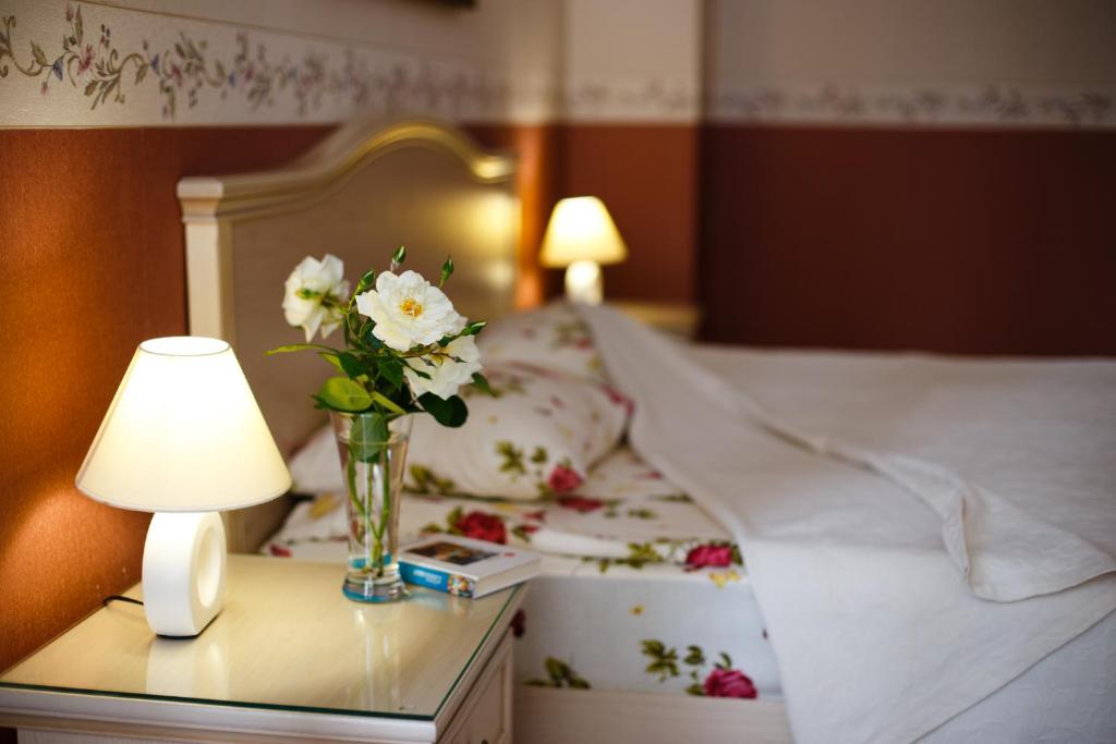 una cama con un jarrón de flores sobre una mesa con una lámpara en Sparta Hotel en Yalta