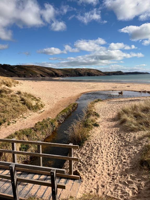 a bench sitting on a sandy beach next to a river at Peaceful stay 5 mins to beach and coast path walks in Pembrokeshire