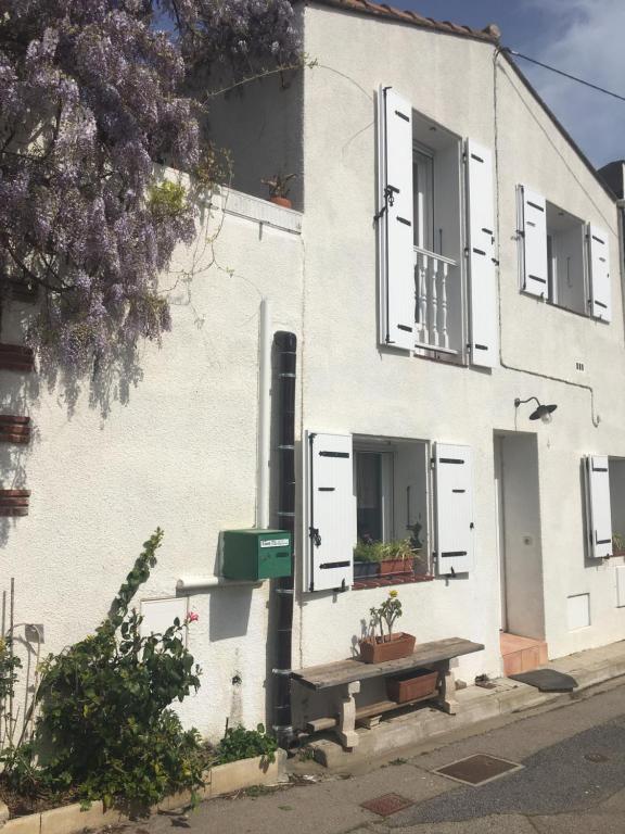 un bâtiment blanc avec des fenêtres blanches à volets et un banc dans l'établissement Cocon, à Saint-Nazaire