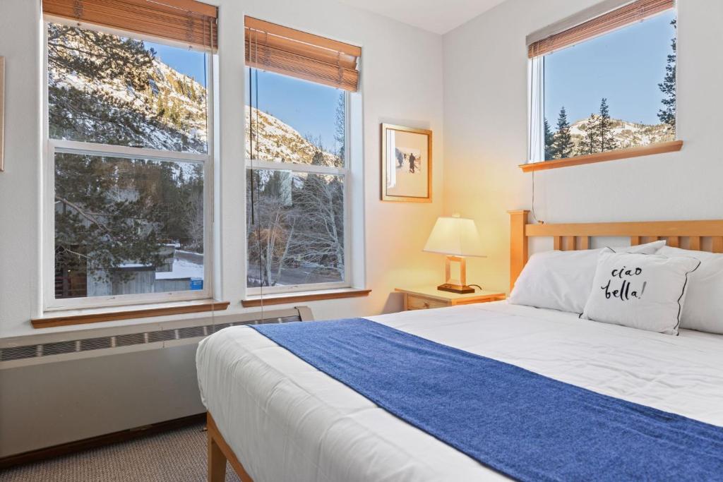 オリンピックバレーにあるPalisades Tahoe Lodge Rentals Premium Fireplace One Bedroom #807のベッドと2つの大きな窓がある寝室