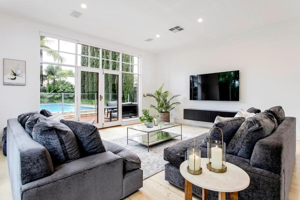 ein Wohnzimmer mit zwei Sofas und einem Fernseher in der Unterkunft Oasis - Luxe living, with pool - walk to cafes in Rose Park