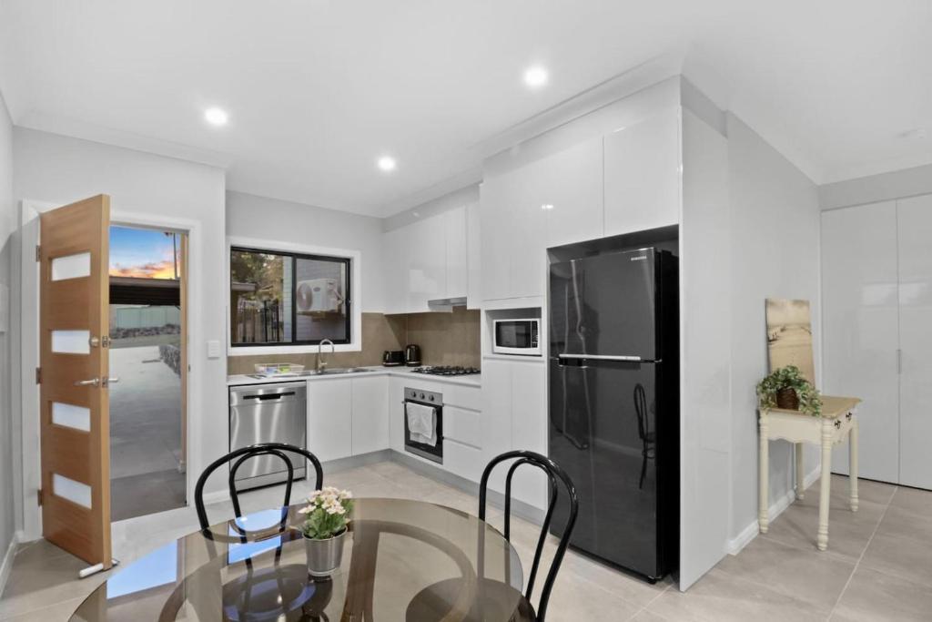 a kitchen with white walls and a black refrigerator at Modern Haven in Toronto