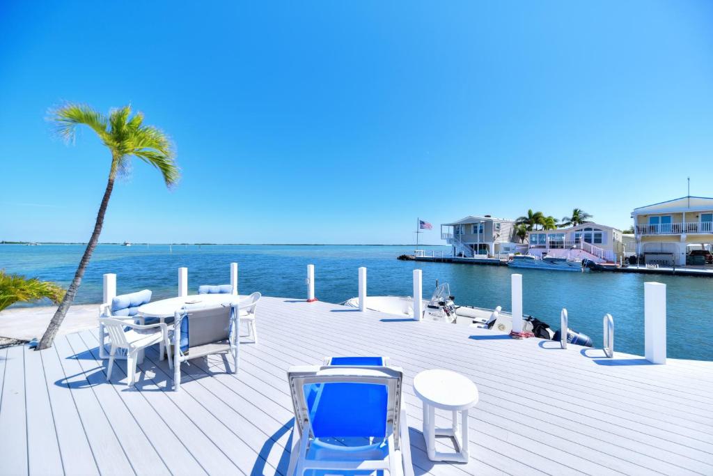 a wooden deck with chairs and a table and a palm tree at Windy Point Oceanfront in Geiger Key in Big Coppitt Key