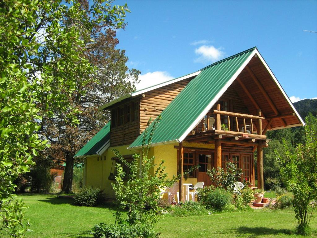 uma casa com um telhado verde num quintal verde em Cabaña Ruca Kushe em Lago Puelo