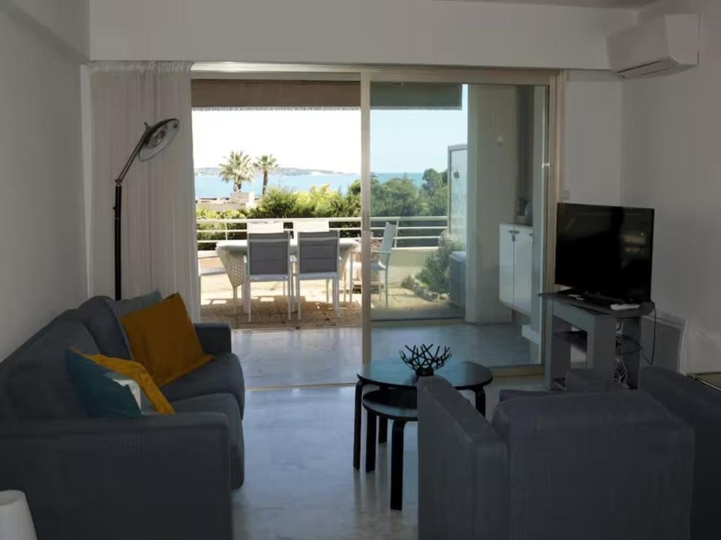 un salon avec un canapé, une télévision et une table dans l'établissement Apartment in Golfe Juan with Sea View, à Vallauris