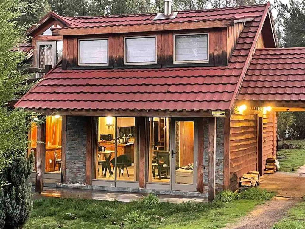 a wooden house with a red roof at Cheerful Santa Juana Cabin in Santa Juana