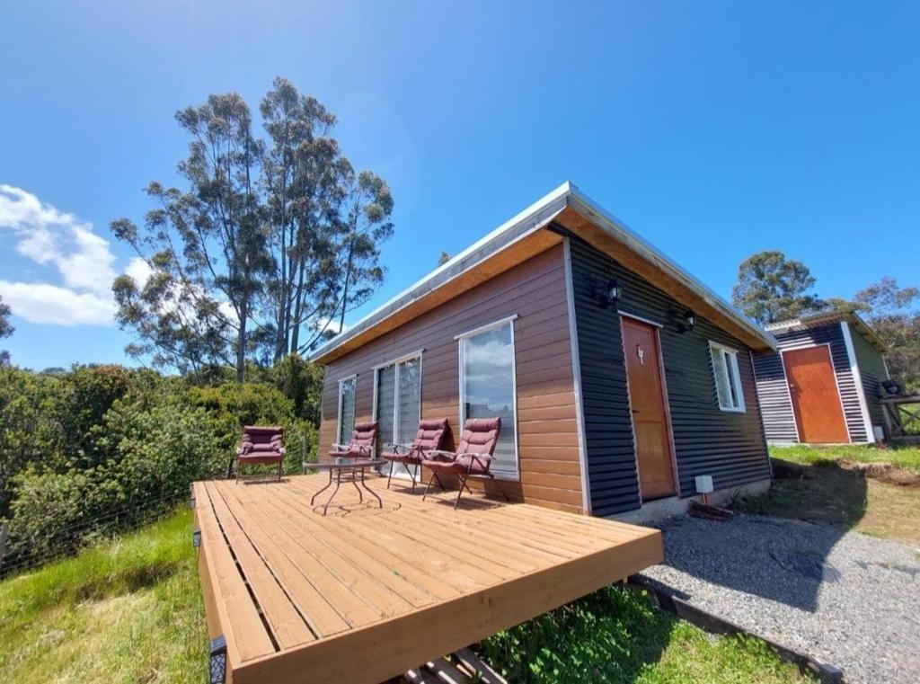a tiny house with a deck and two chairs at Cabaña privada con acceso a playa in Quilquico