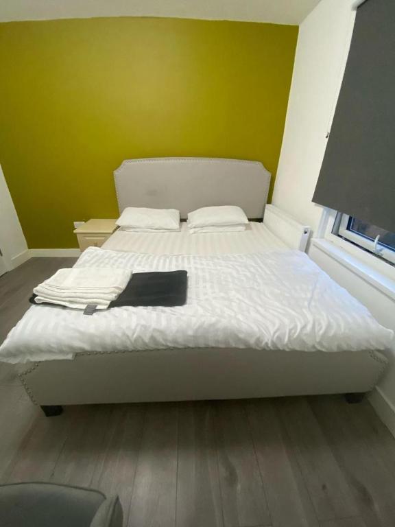 a bedroom with a white bed with a yellow wall at Heathrow Close Comfort Room in Stanwell