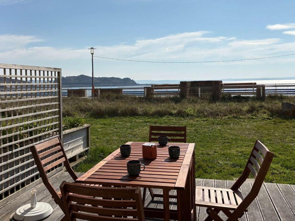 - une table et des chaises en bois sur une terrasse avec vue sur l'océan dans l'établissement Appartement 56m² bord de mer avec terrasse, parking privé, WiFi - FR-1-542-67, à Trébeurden