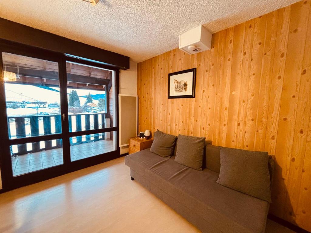 un salon avec un canapé et une grande fenêtre dans l'établissement Appartement cosy à Autrans, animaux admis, parking, 4 pers - FR-1-737-94, à Autrans