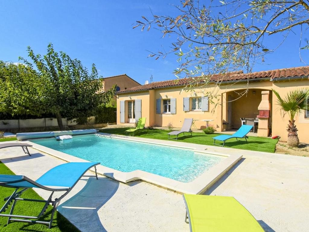 une piscine avec des chaises et une maison dans l'établissement Villa agréable près d'Avignon avec piscine privative et WiFi - FR-1-708-85, à Avignon