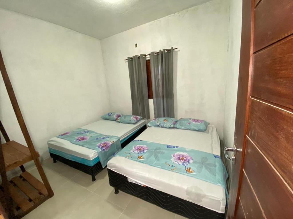 two beds in a small room with a door at Casa por temporada Barra Nova in Marechal Deodoro