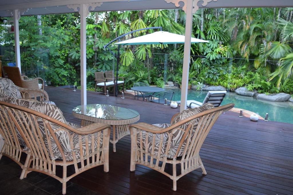 un patio con mesa, sillas y sombrilla en South Pacific Bed & Breakfast, en Clifton Beach