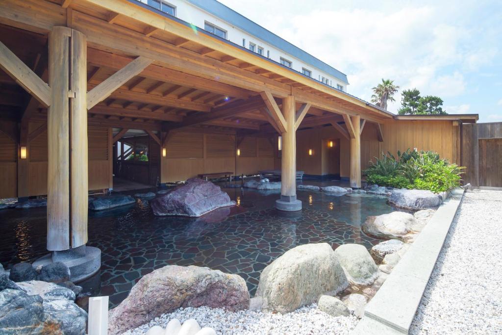 a building with a pool of water with rocks at Hotel Izukyu in Shimoda