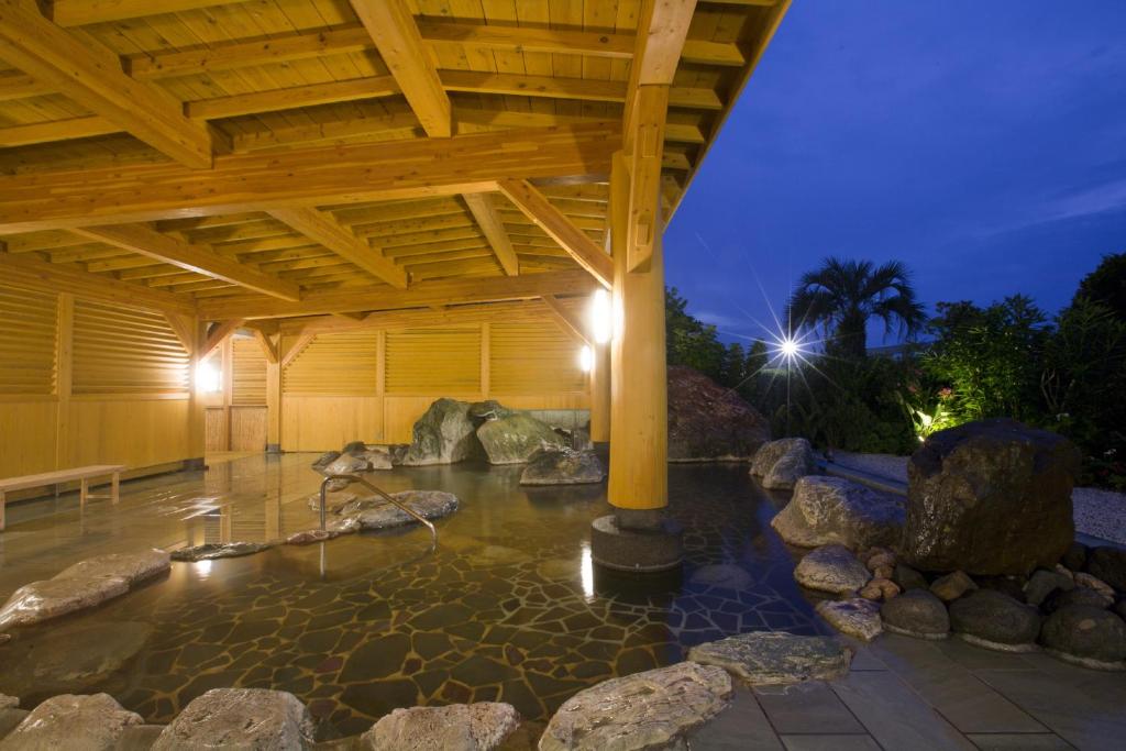 a patio with a pool of water under a wooden roof at Hotel Izukyu in Shimoda