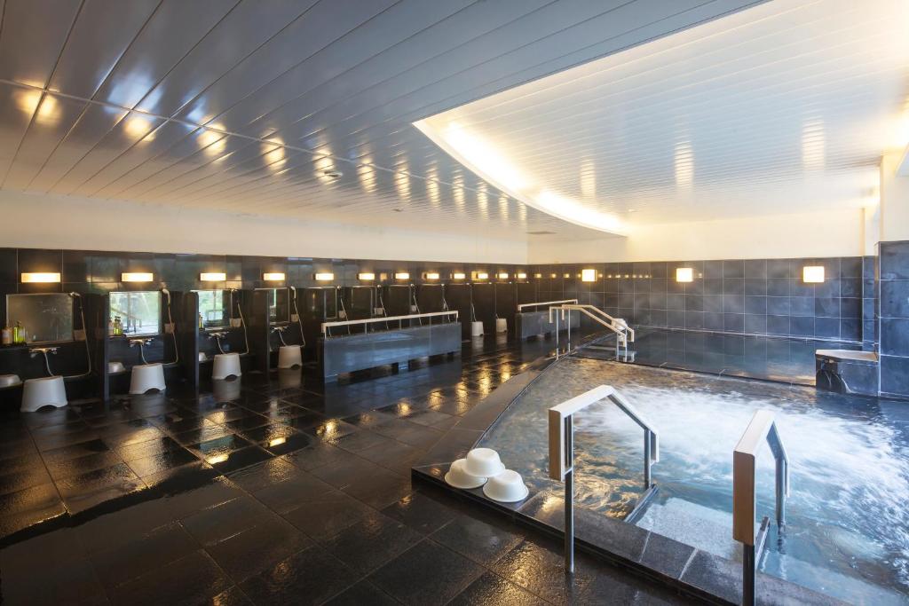 a large bathroom with a hot tub and toilets at Hotel Izukyu in Shimoda