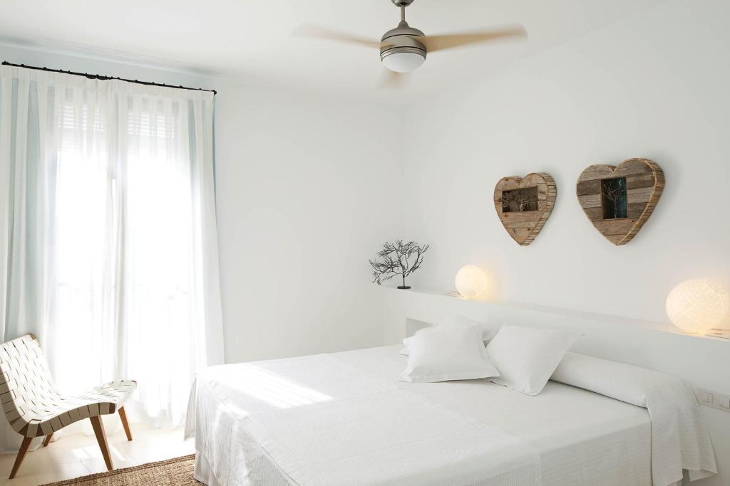 a white bedroom with a bed and two hearts on the wall at Hotel Es Marès in Sant Francesc Xavier