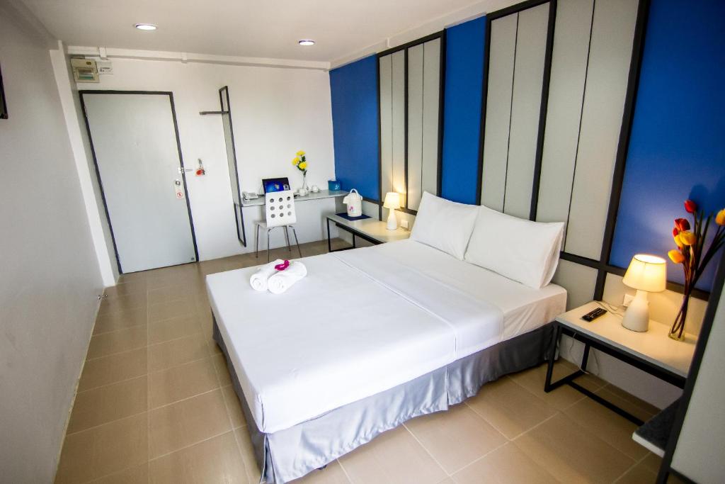 uma grande cama branca num quarto com paredes azuis em Regent Ngamwongwan Hotel em Nonthaburi